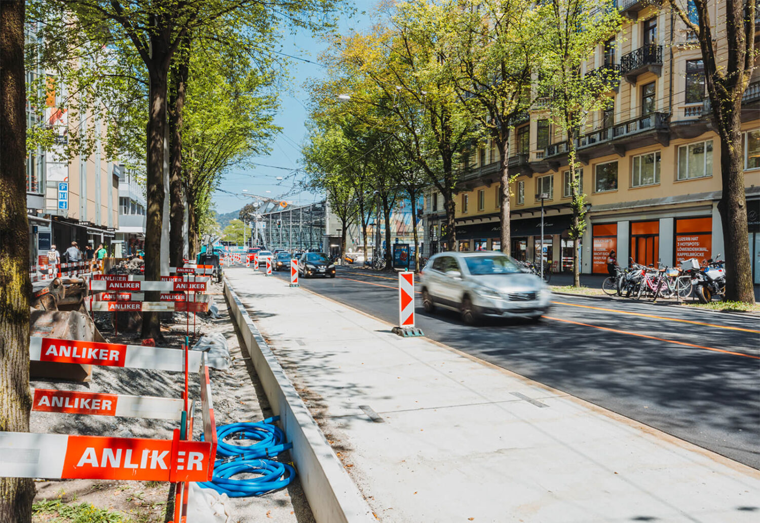 Neue, eingebaute Betonplatten für eine Busspur im innerstädtischen Strassenraum bei Tageslicht und vorbeifahrendem Verkehr.