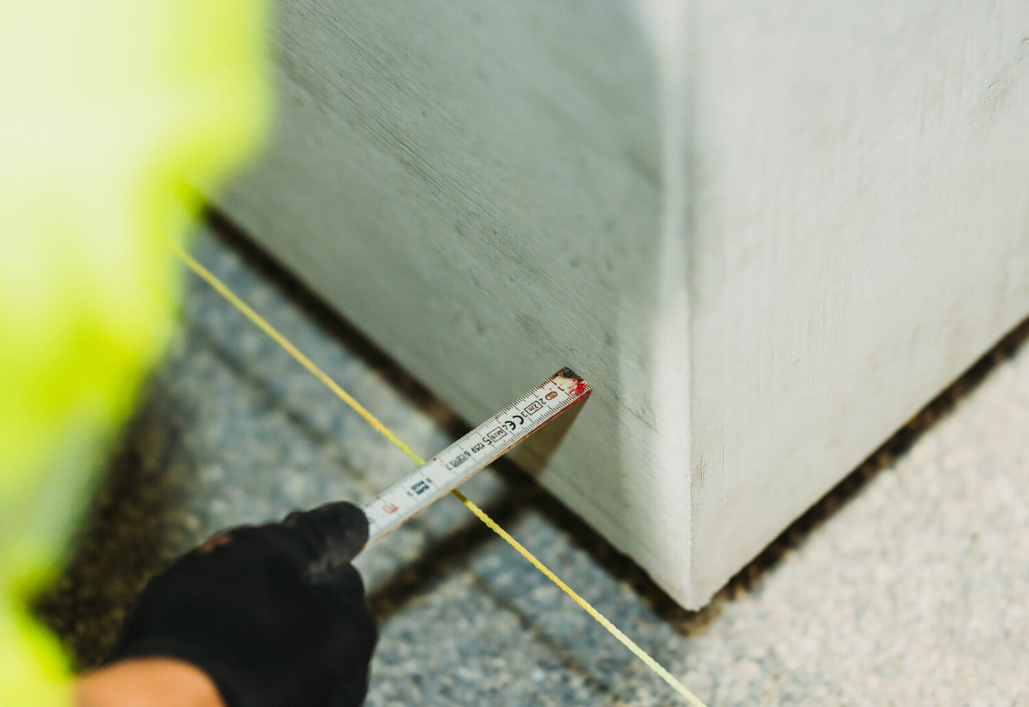 Bauarbeiter misst den genauen Abstand und die Ausrichtung einer vorgefertigten Betonplatte mit dem Doppelmeter an einer Richtschnur ab.
